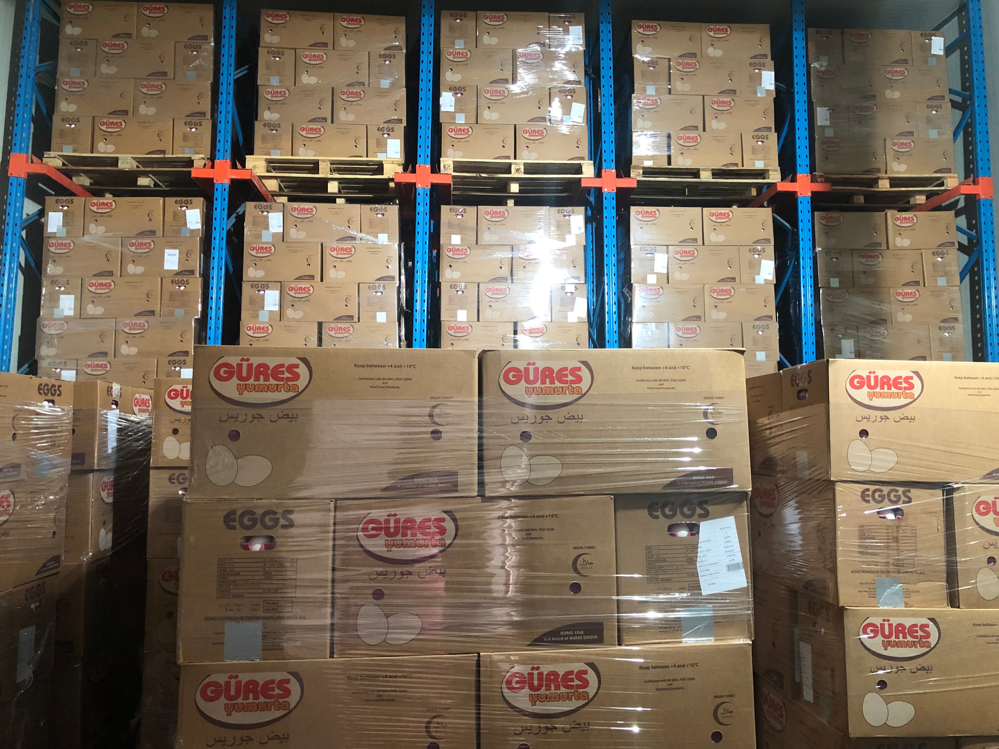 Stack of cardboard boxes neatly arranged in a warehouse setting with metal shelving